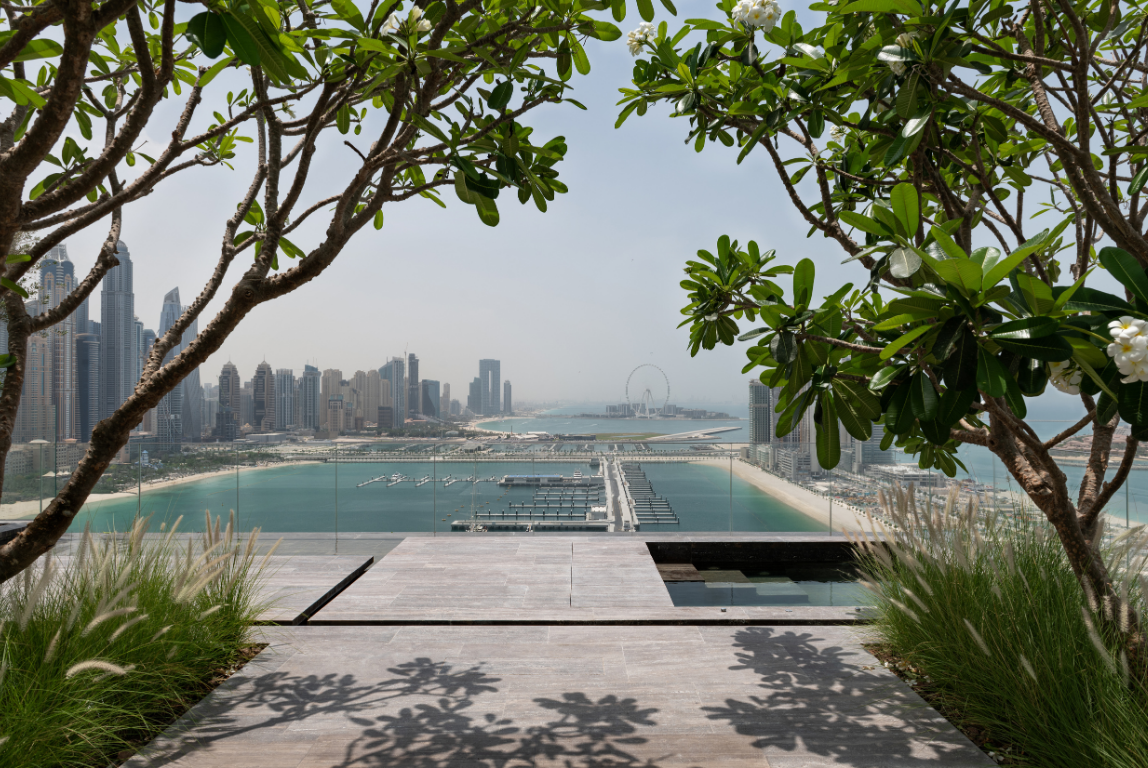 Landscaped terrace overlooking Dubai Marina, framed by mature planting with views across the waterfront and skyline.