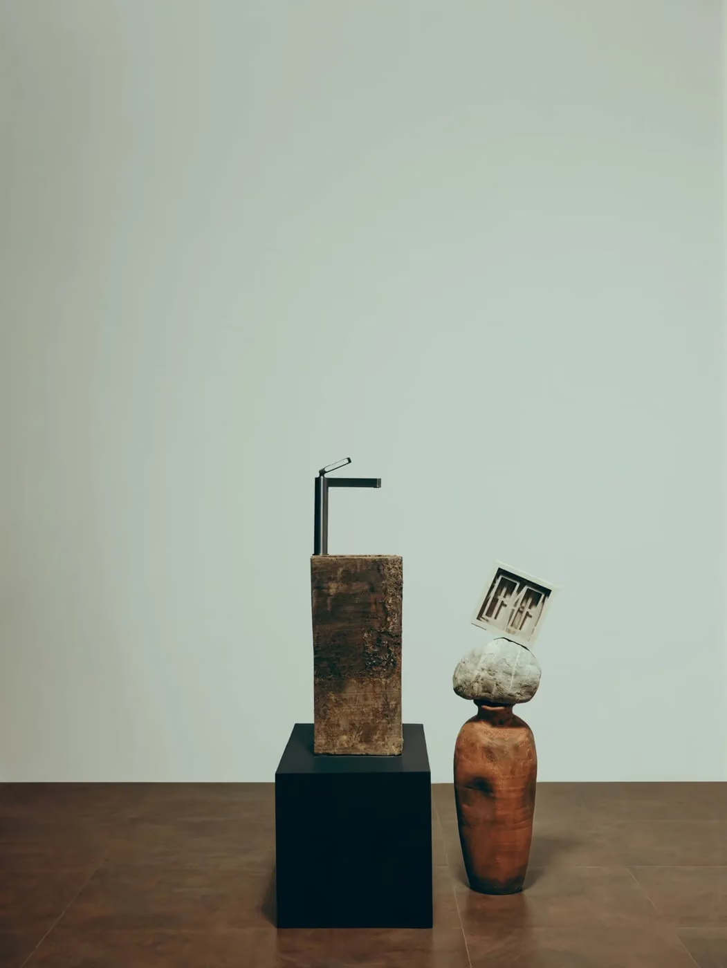 Tall faucet on a stone column beside a terracotta vase