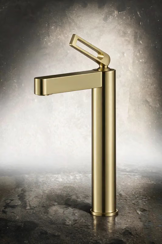 Brushed gold tall basin mixer with an open loop handle against a textured grey backdrop