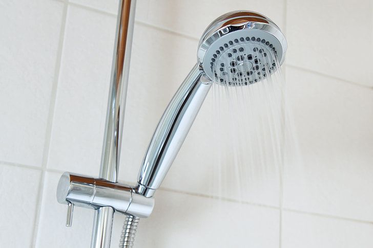 Chrome hand shower on a wall rail with water flowing