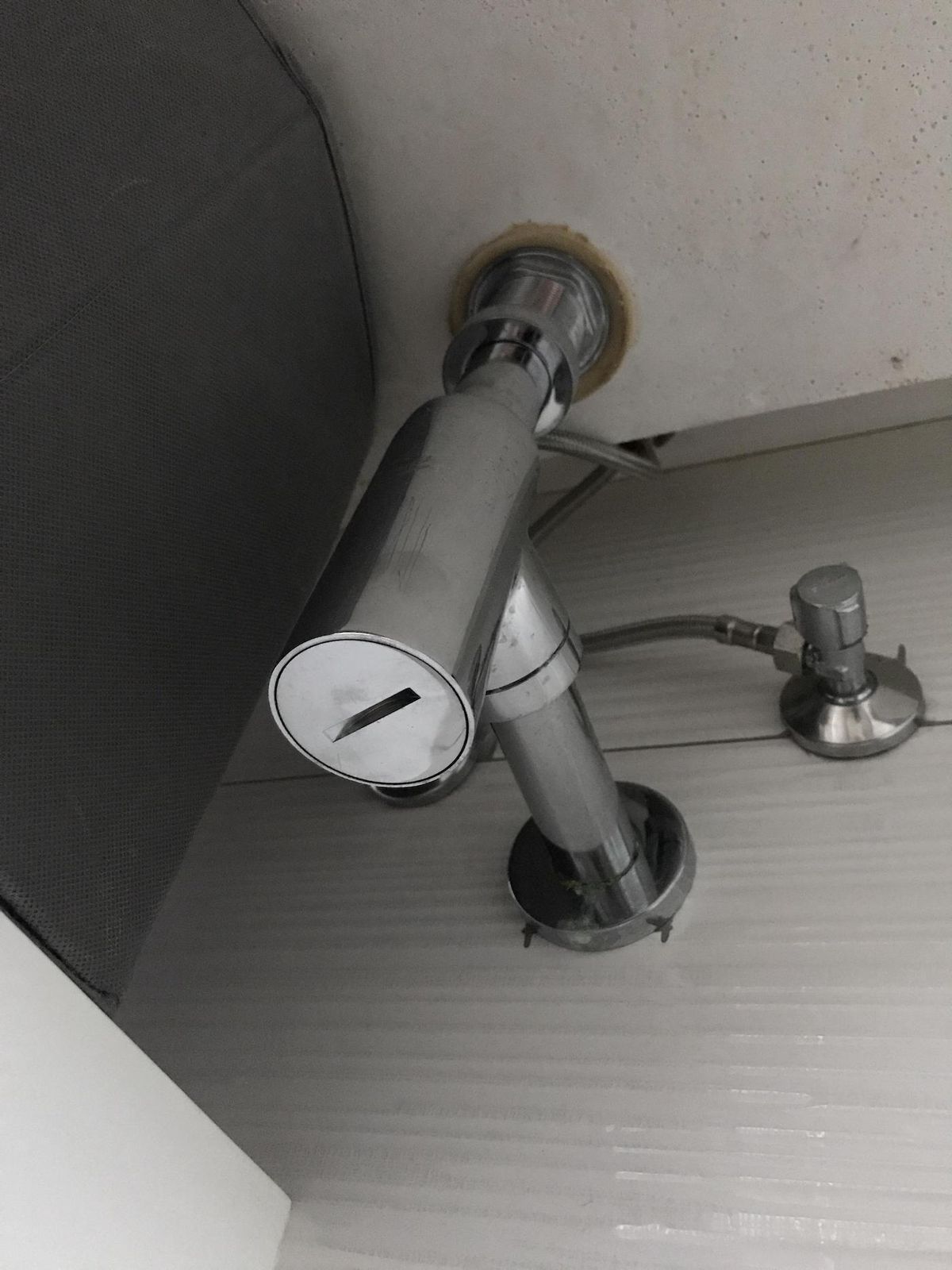 Chrome bottle trap fitted under a basin, seen from below