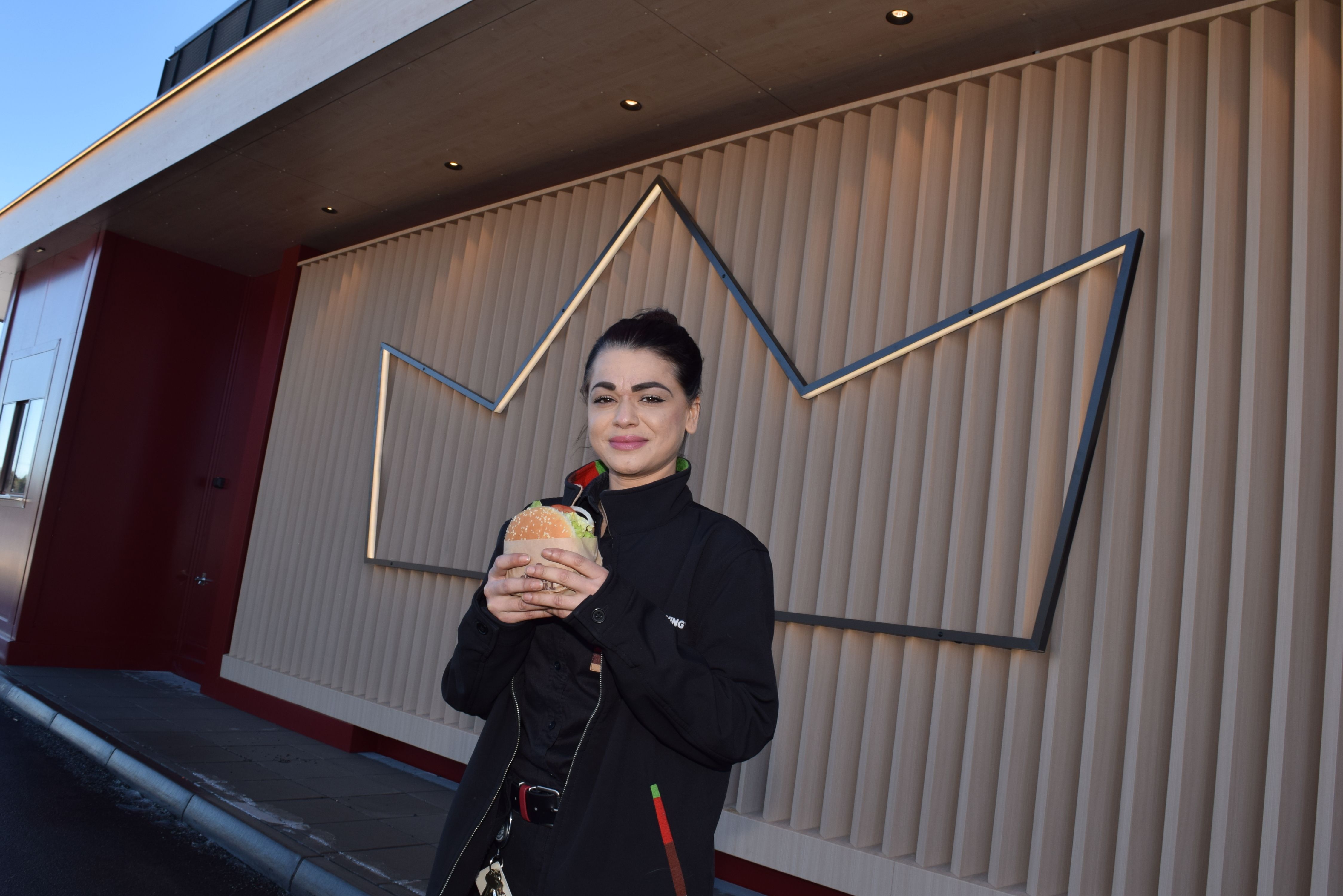 Restaurantsjef Fakiha Mirza utenfor bygget, holder en burger