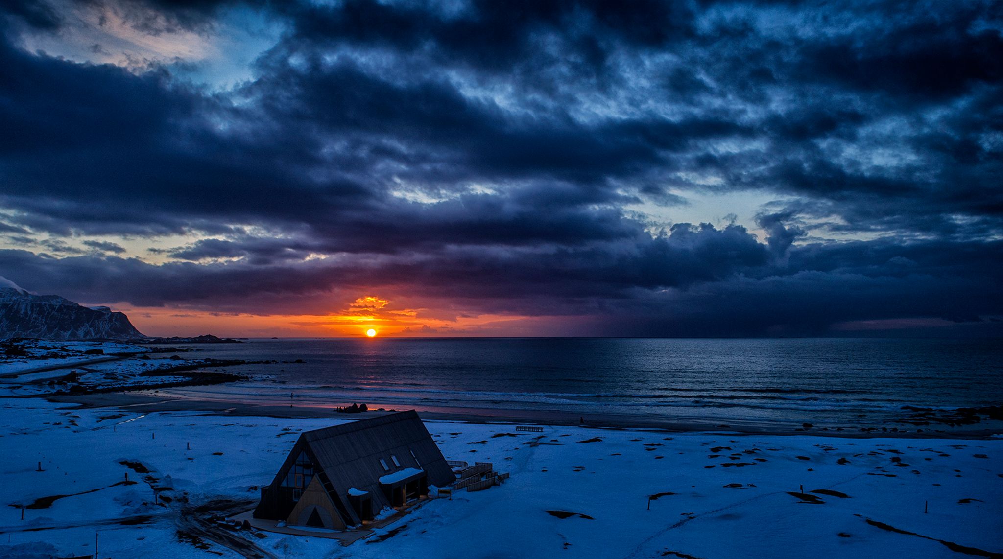 Solnedgang og vakker himmel i bakgrunnen av Lofoten Beach Camp vinterstid. 