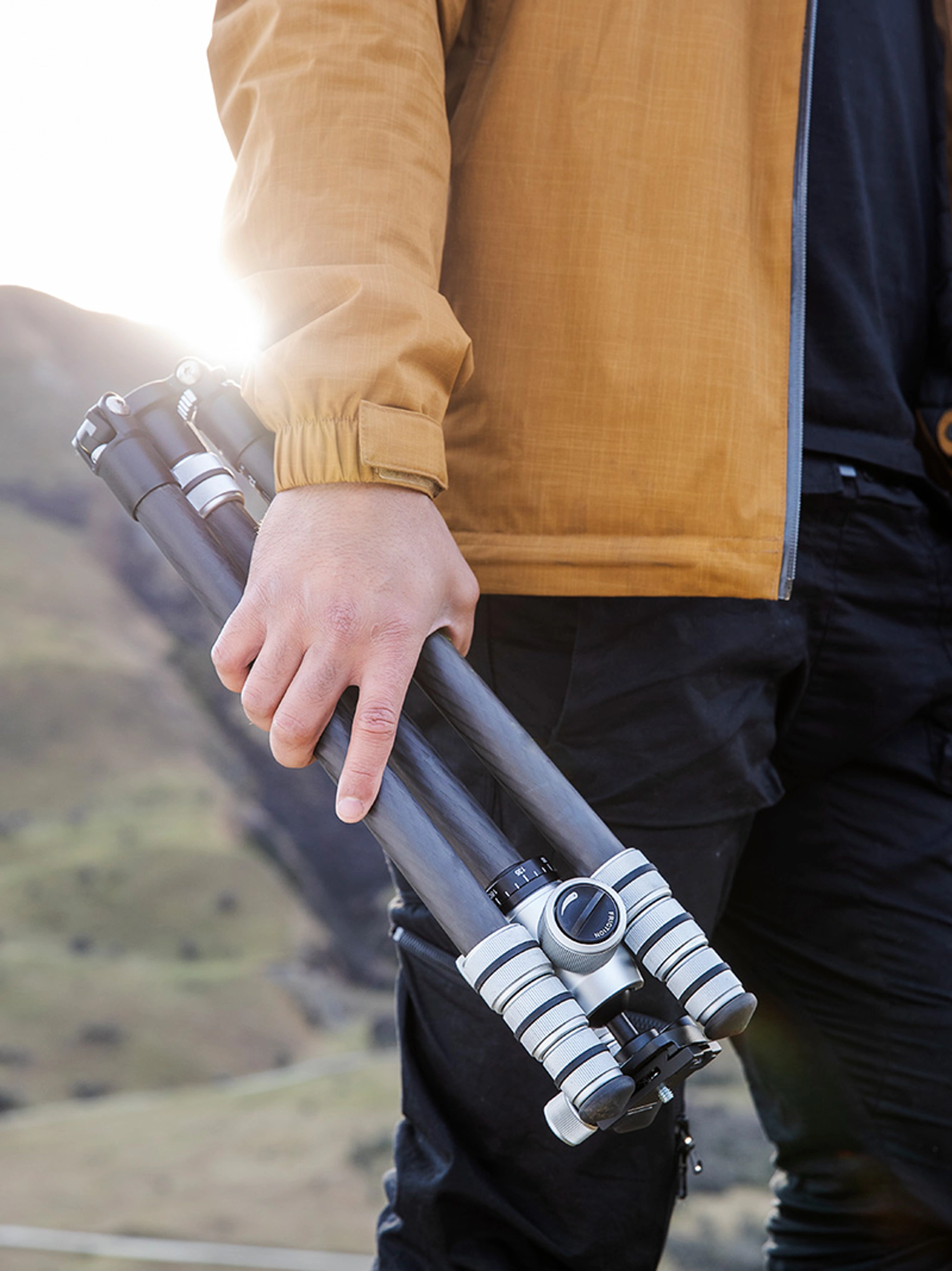 Photographer hiking in the mountains holding a tripod