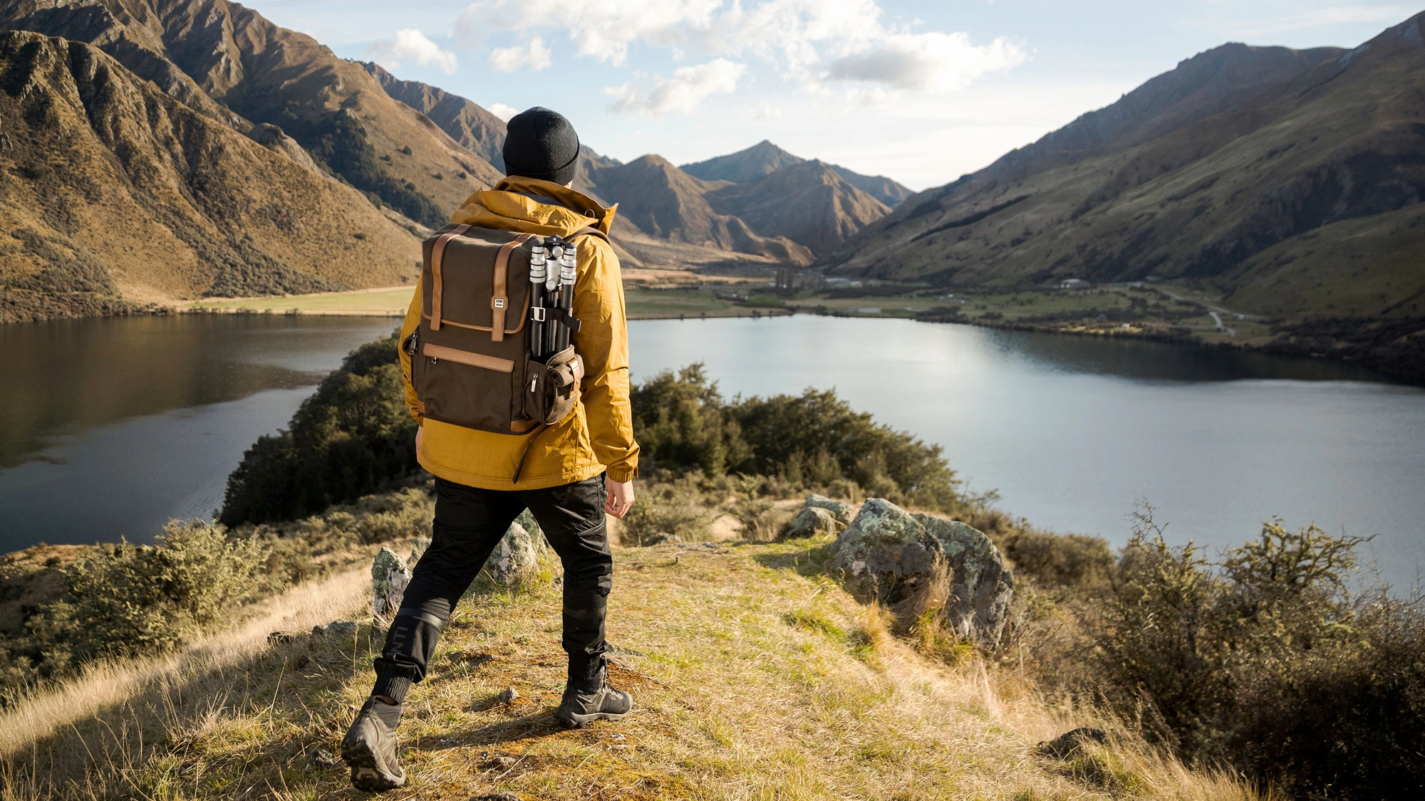 male hiking in the mountains with camera backpack and tripod