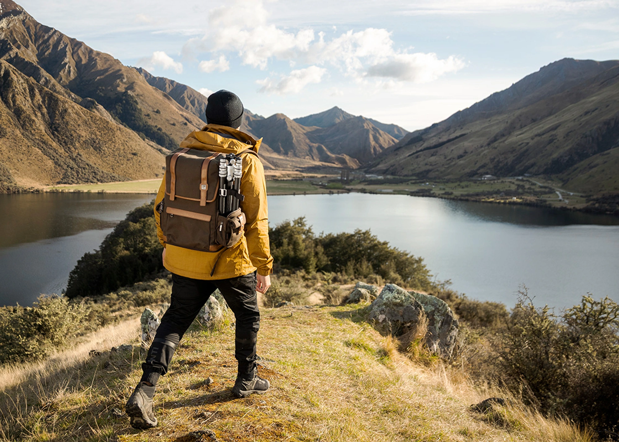 male hiking in the mountains with camera backpack and tripod