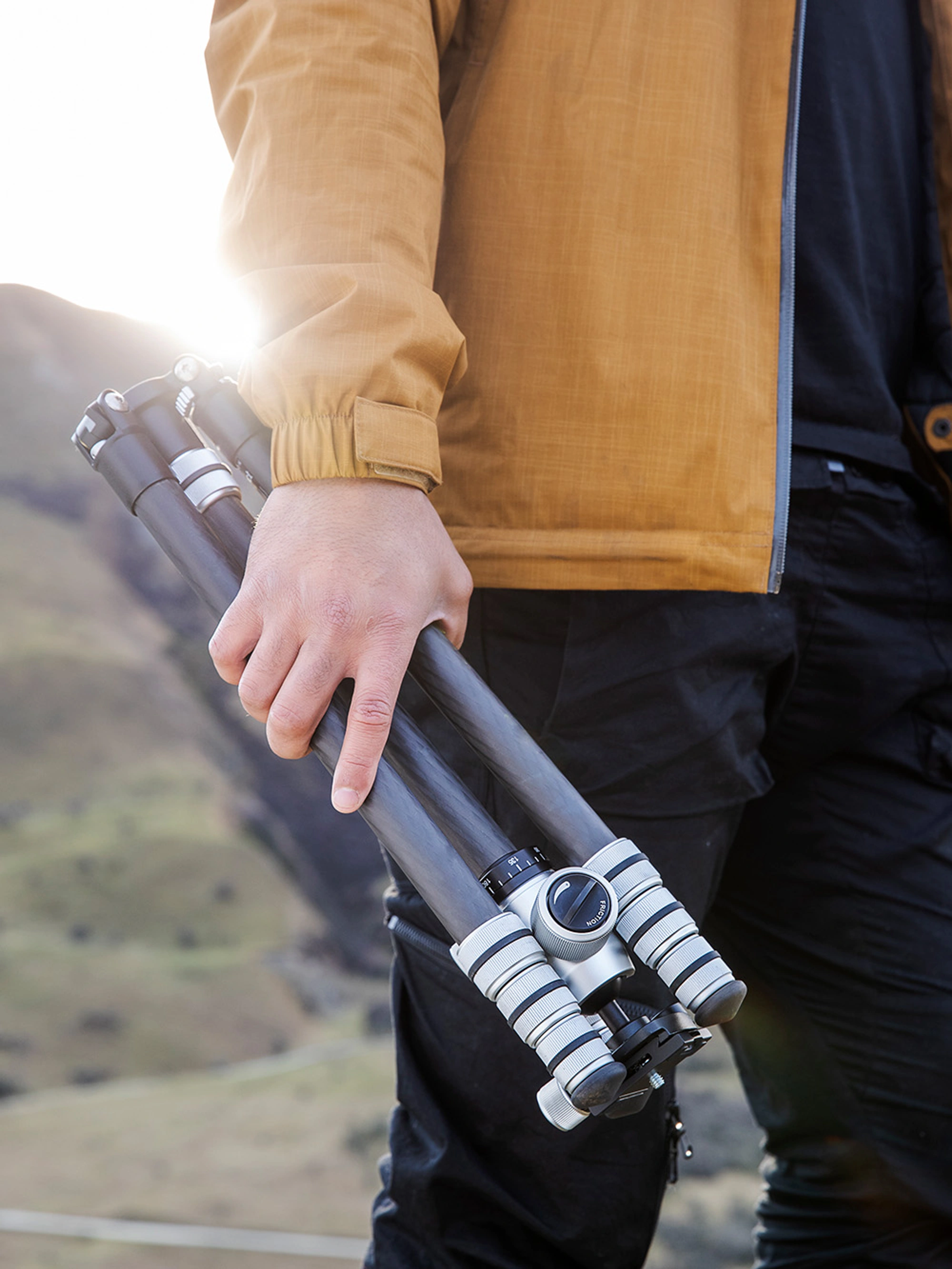 Photographer hiking in the mountains holding a tripod