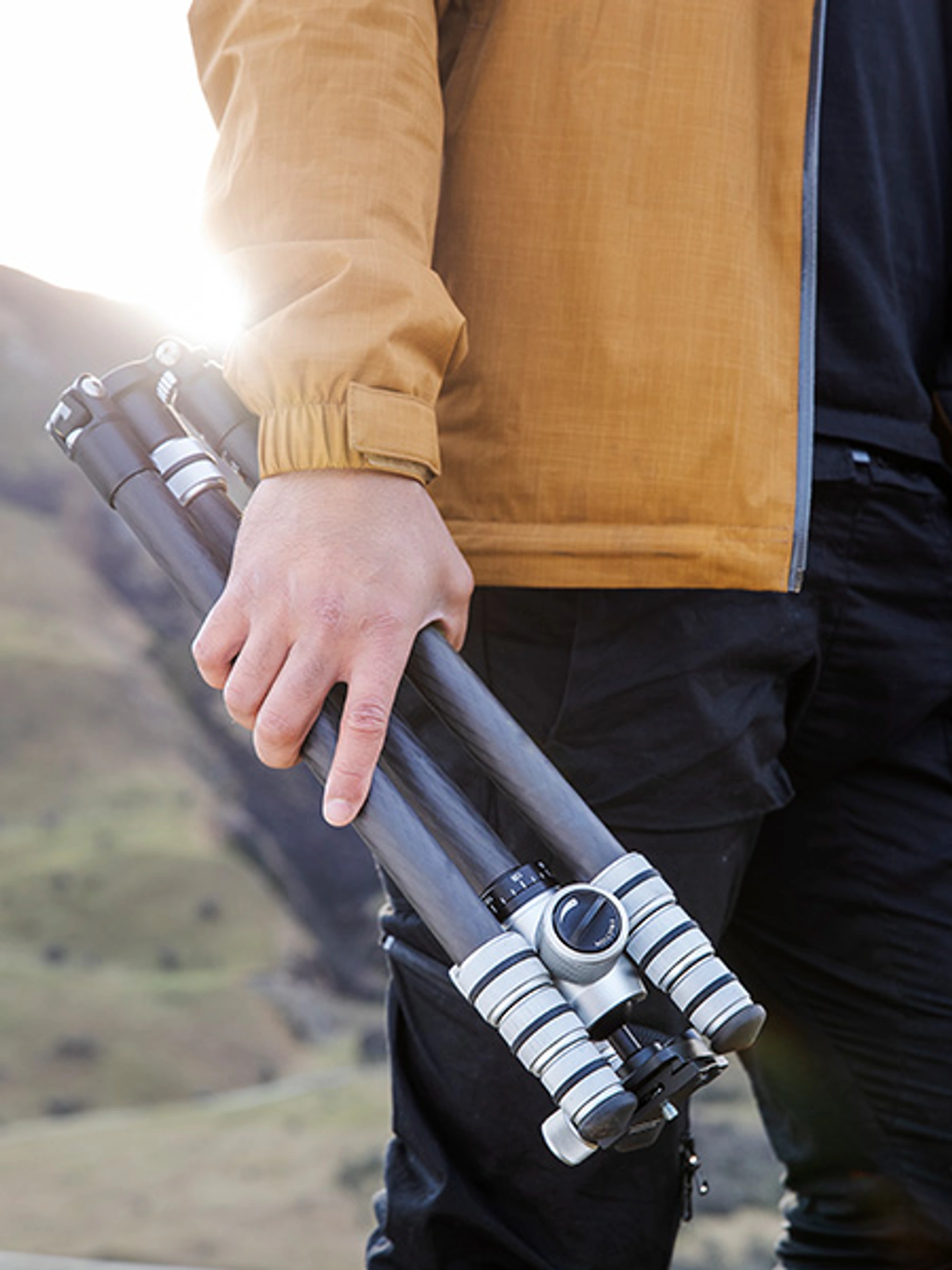 Photographer hiking in the mountains holding a tripod