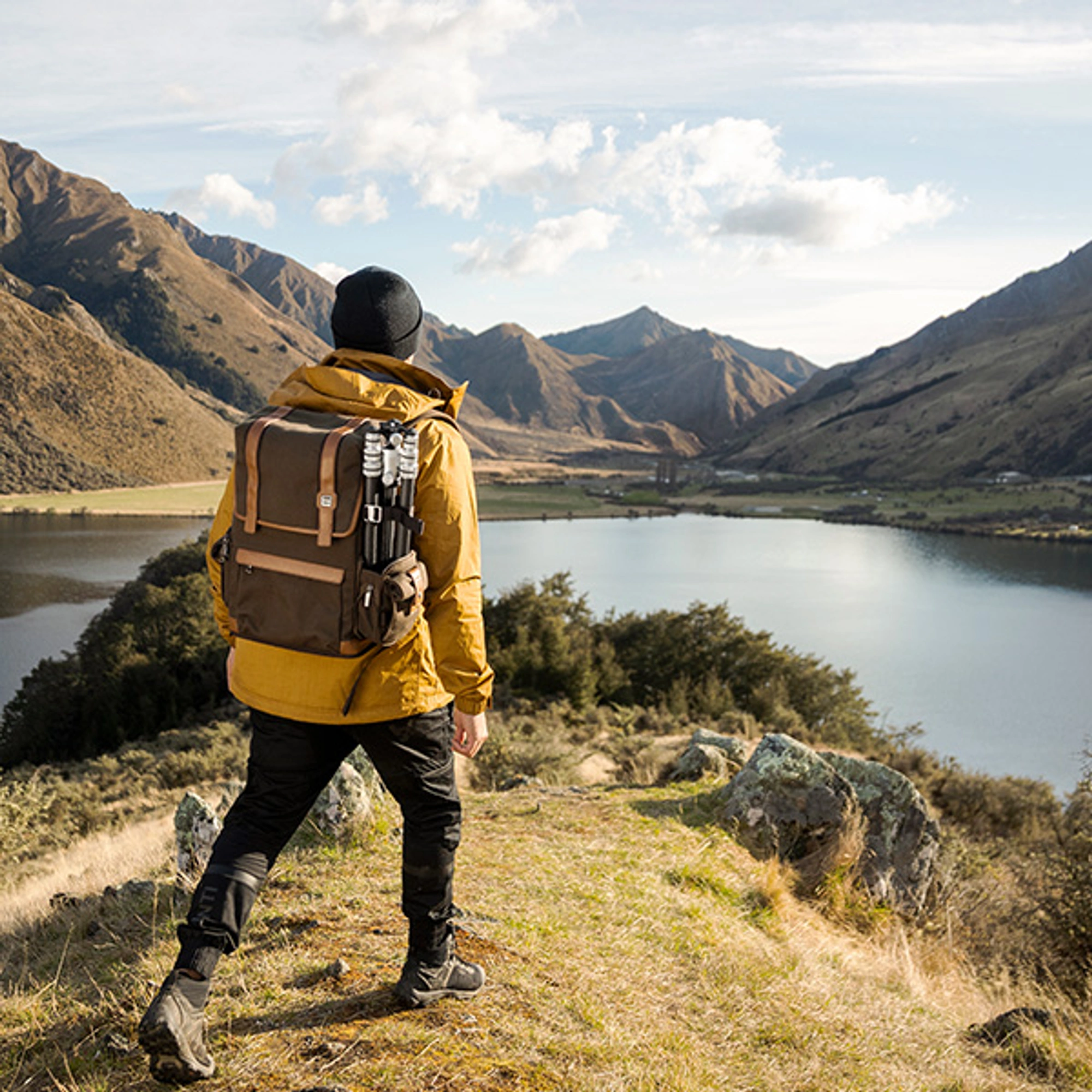 male hiking in the mountains with camera backpack and tripod