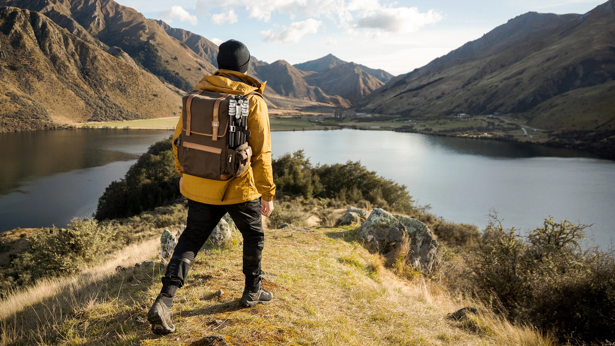 male hiking in the mountains with camera backpack and tripod