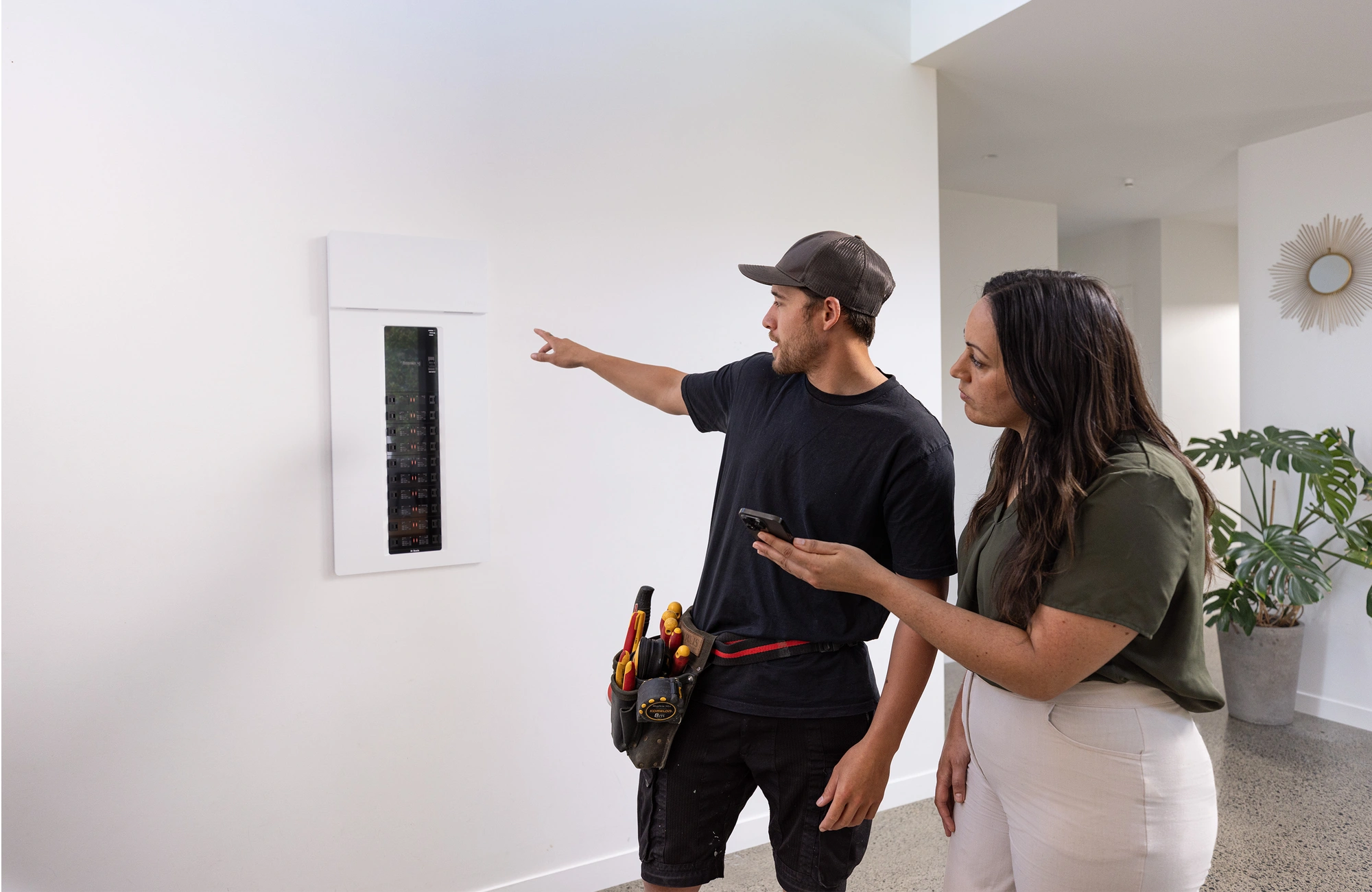 electrician reviewing smart panel circuit board with customer
