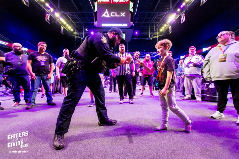 A crowd enjoying a police officer play "rock-paper-scissors" with a child