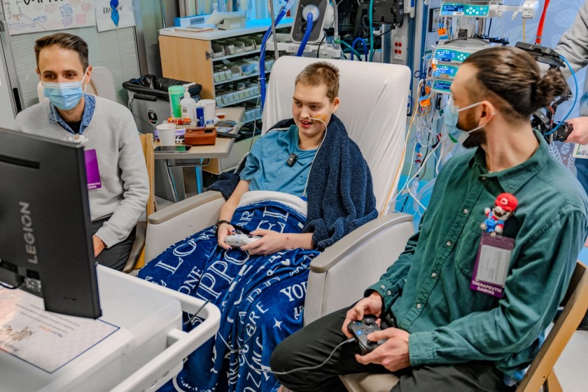 A patient in a children's hospital playing games with hospital staff on a GO Kart.