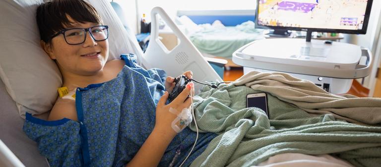A child plays video games in a hospital alongside a Gamers Outreach device.
