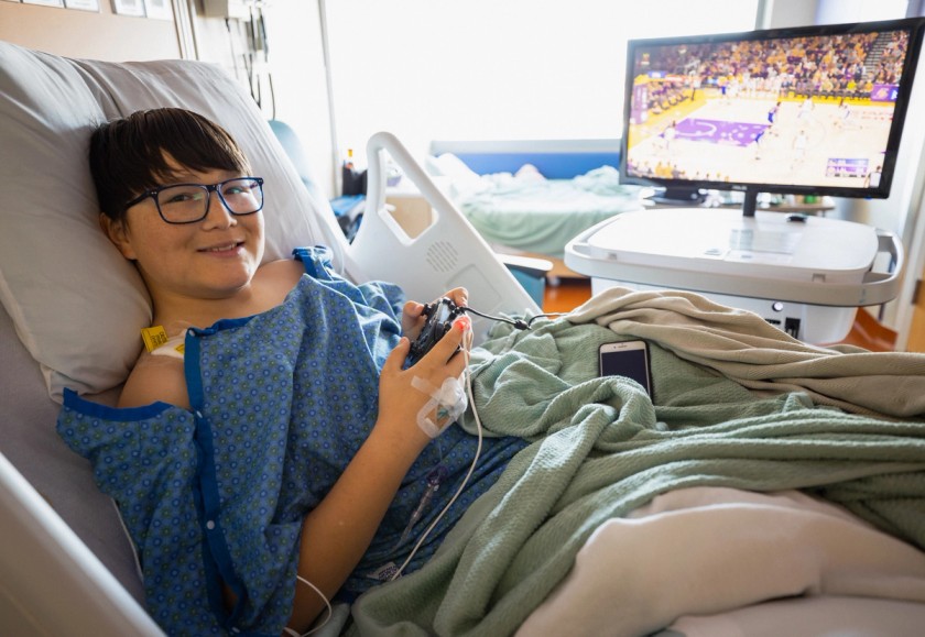 A child plays video games in a hospital alongside a Gamers Outreach device.
