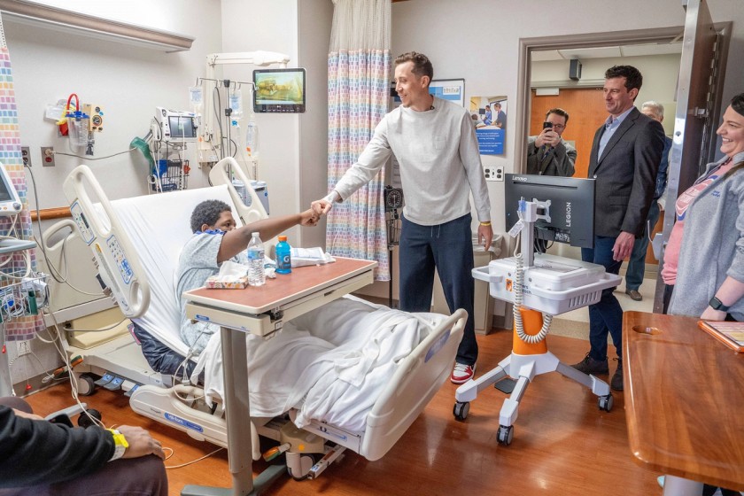 Child at the hospital gives a fist bump to a professional athlete.