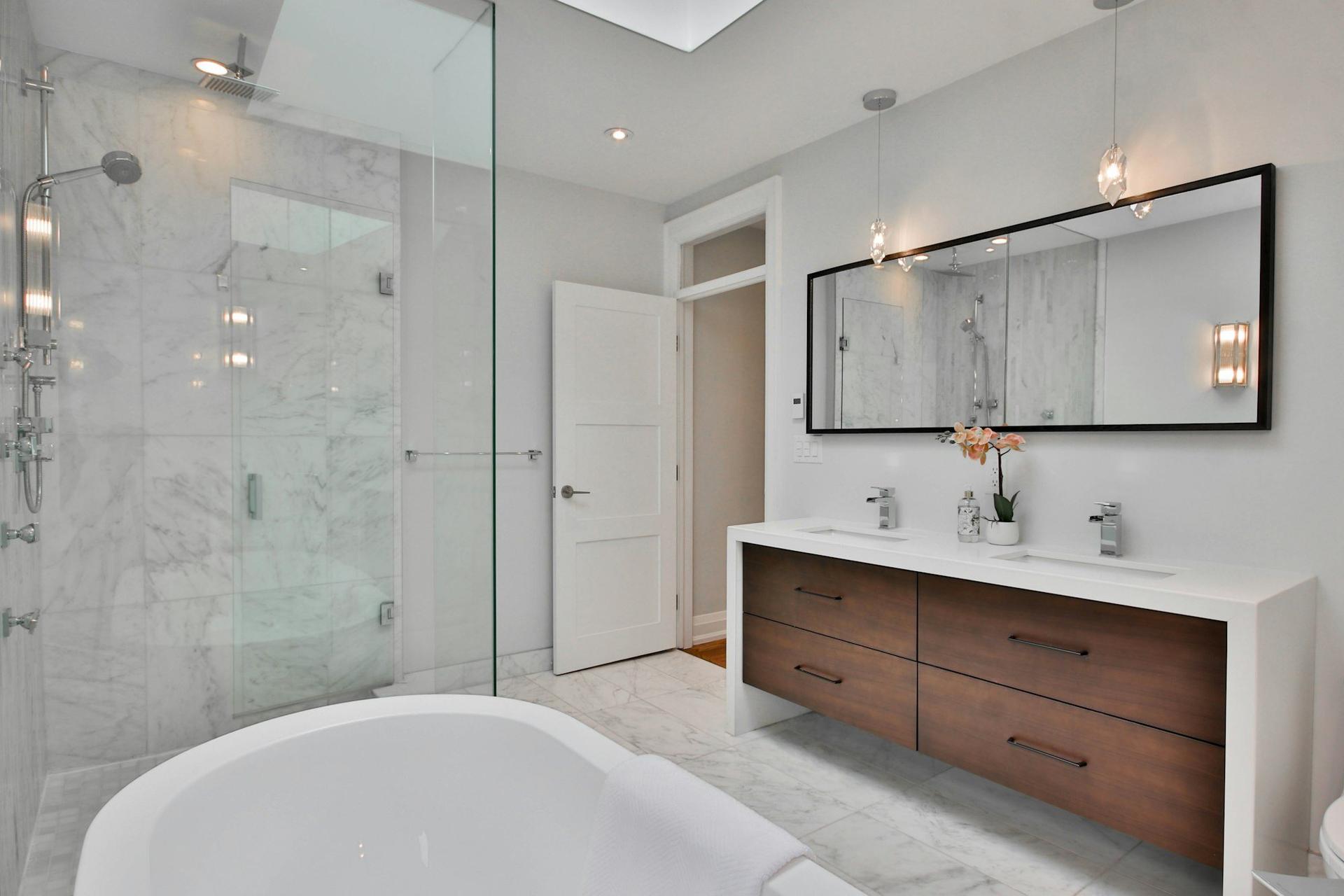 A bright modern bathroom with a freestanding bath, walk-in shower and wooden vanity unit.