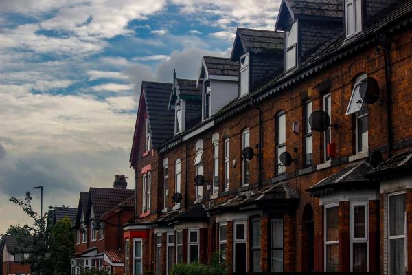 A row of red-brick terraced houses under a cloudy sky.