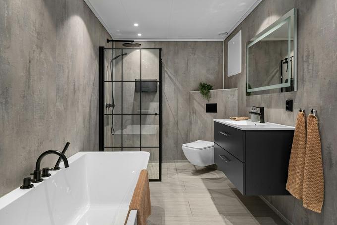 A refurbished bathroom with a freestanding bath, black-framed shower screen and wall-hung vanity.