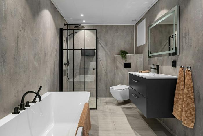 A refurbished bathroom with a freestanding bath, black-framed shower screen and wall-hung vanity.