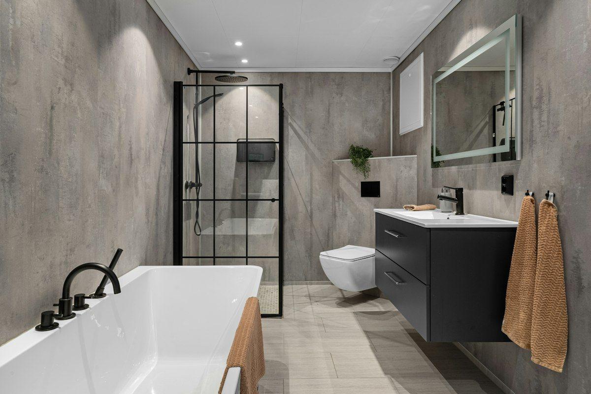 A refurbished bathroom with a freestanding bath, black-framed shower screen and wall-hung vanity.