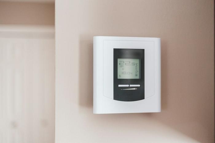 A digital room thermostat on a wall showing 22.5 degrees.