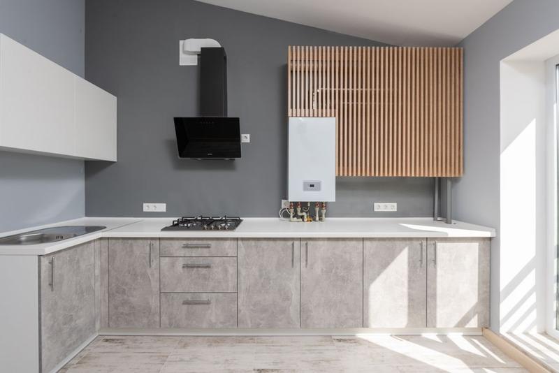 A modern kitchen with a white combi boiler mounted on the wall beside the cabinets.