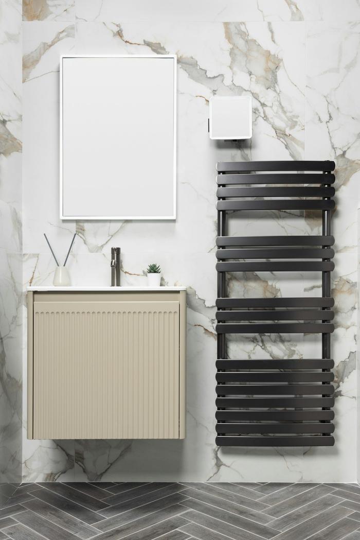 A bathroom with a black heated towel rail beside a cream vanity unit and marble-effect tiles.