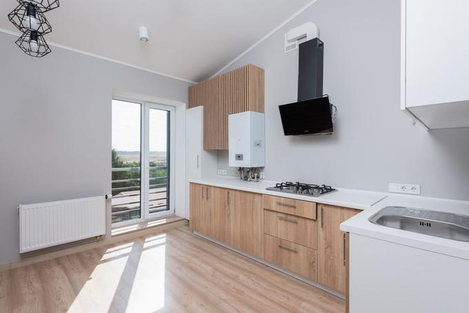 A newly fitted white wall-mounted boiler in a bright kitchen, with a radiator under the window.
