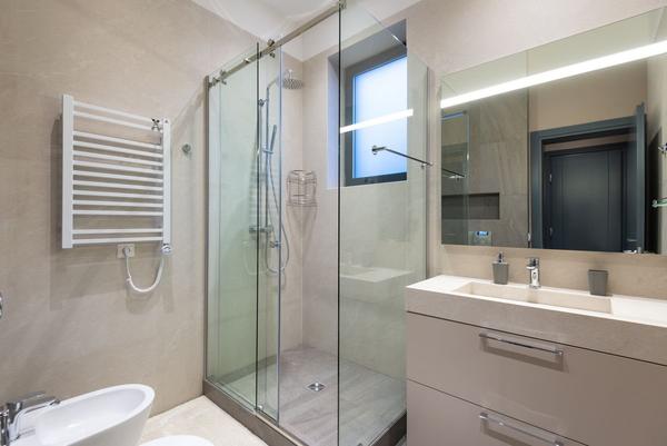 A modern bathroom with a glass shower enclosure, heated towel rail and vanity unit.
