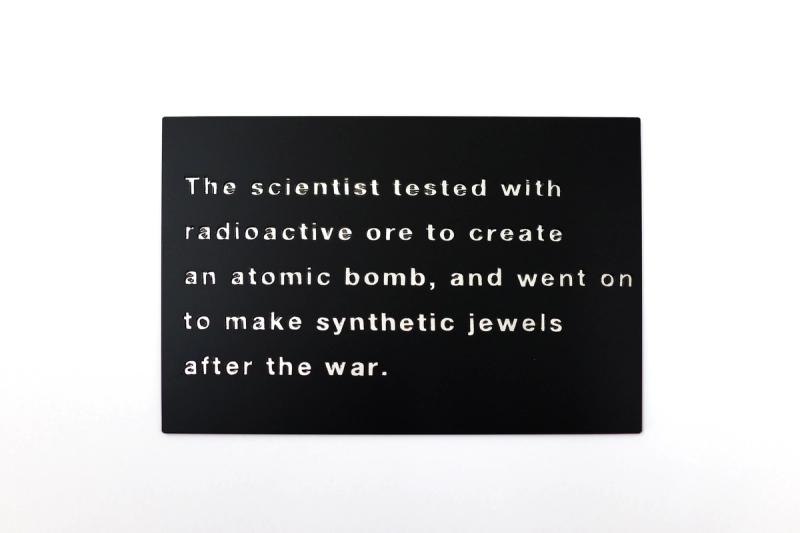 Installation view of displayed artwork titled The scientist tested with radioactive ore to create an atomic bomb, and went on to make synthetic jewels after the war