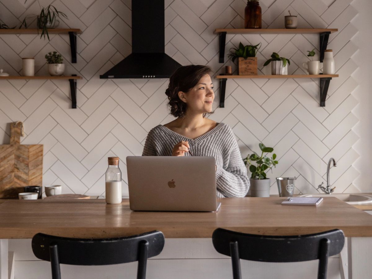 Independent doctor working on laptop in home kitchen