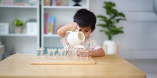 Дете налива течност с чайник