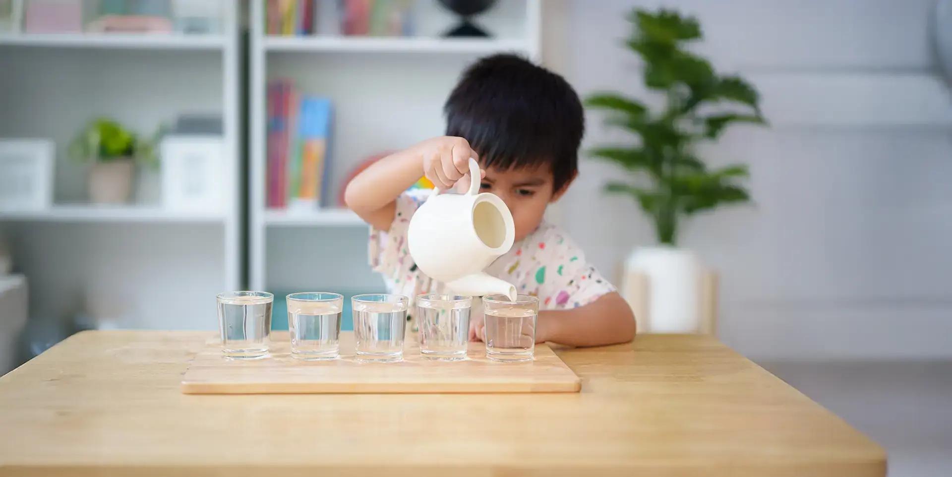 Дете налива течност с чайник