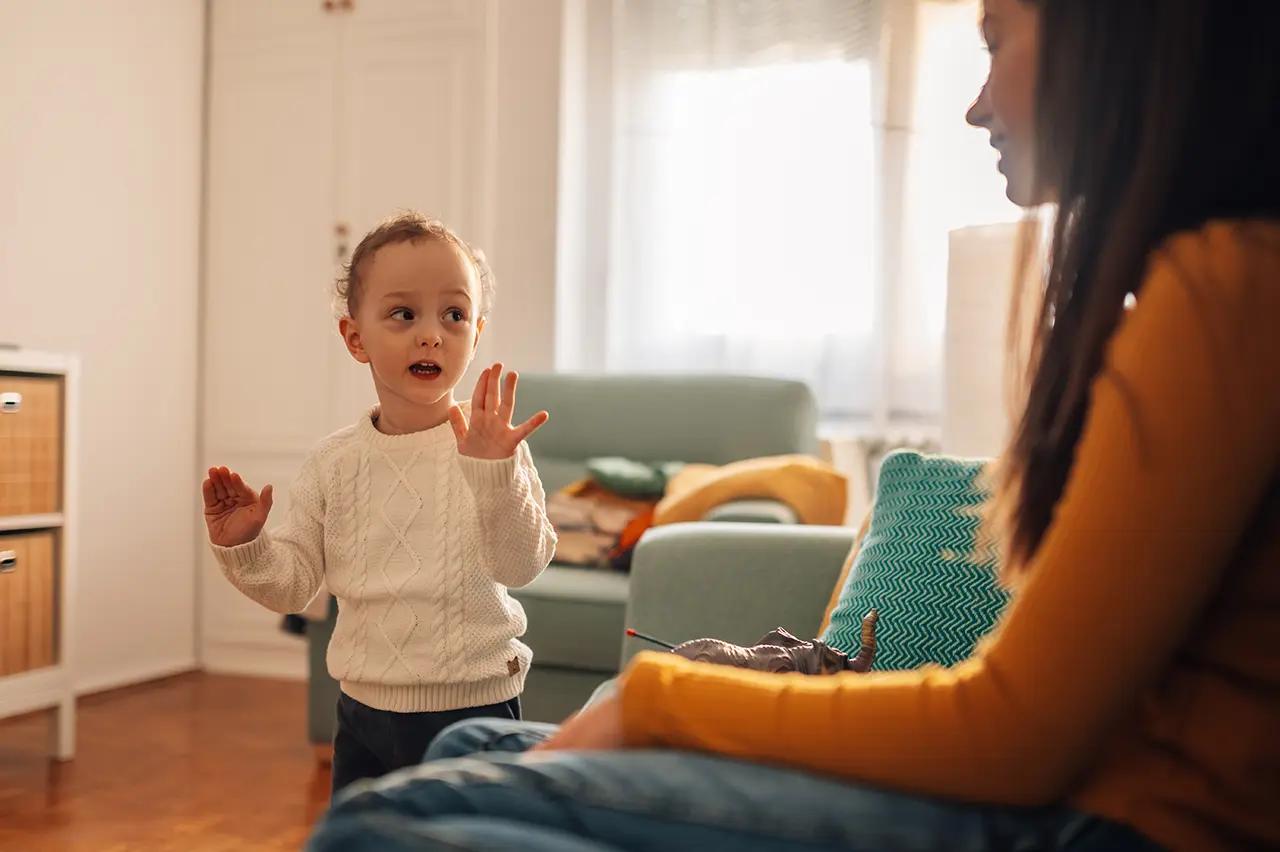 дете държи ръцете си отпред и гледа майка си, до него