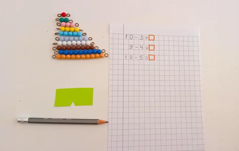 лист с големи квадрати, нанизани на тел мъниста и молив