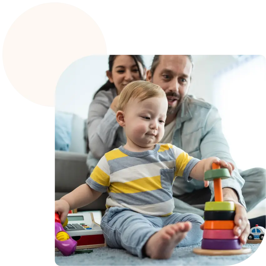 Мъж, жена и бебе играят с монтесори играчка на пода.