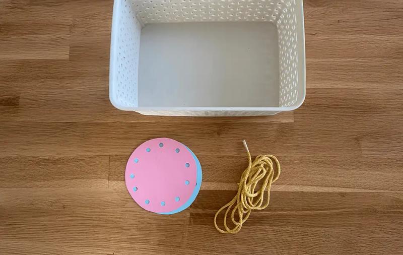 бял панер поставен до розов и син кръг с дупки и връвчица