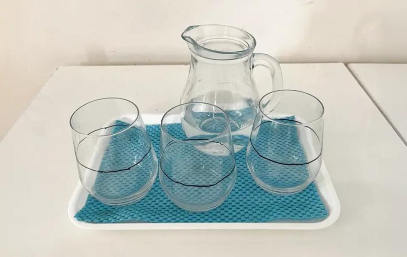 кана с вода и три чаши маркирани посредата върху табла