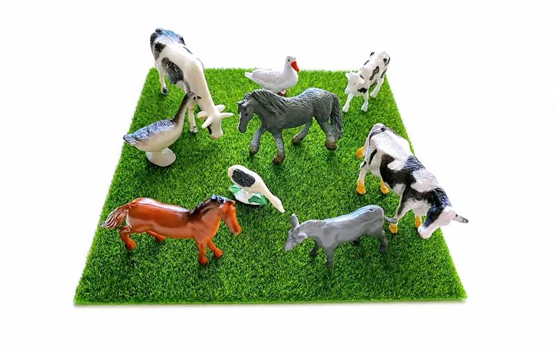 Миниатюрни играчки на животни върху зелена изкуствена трева