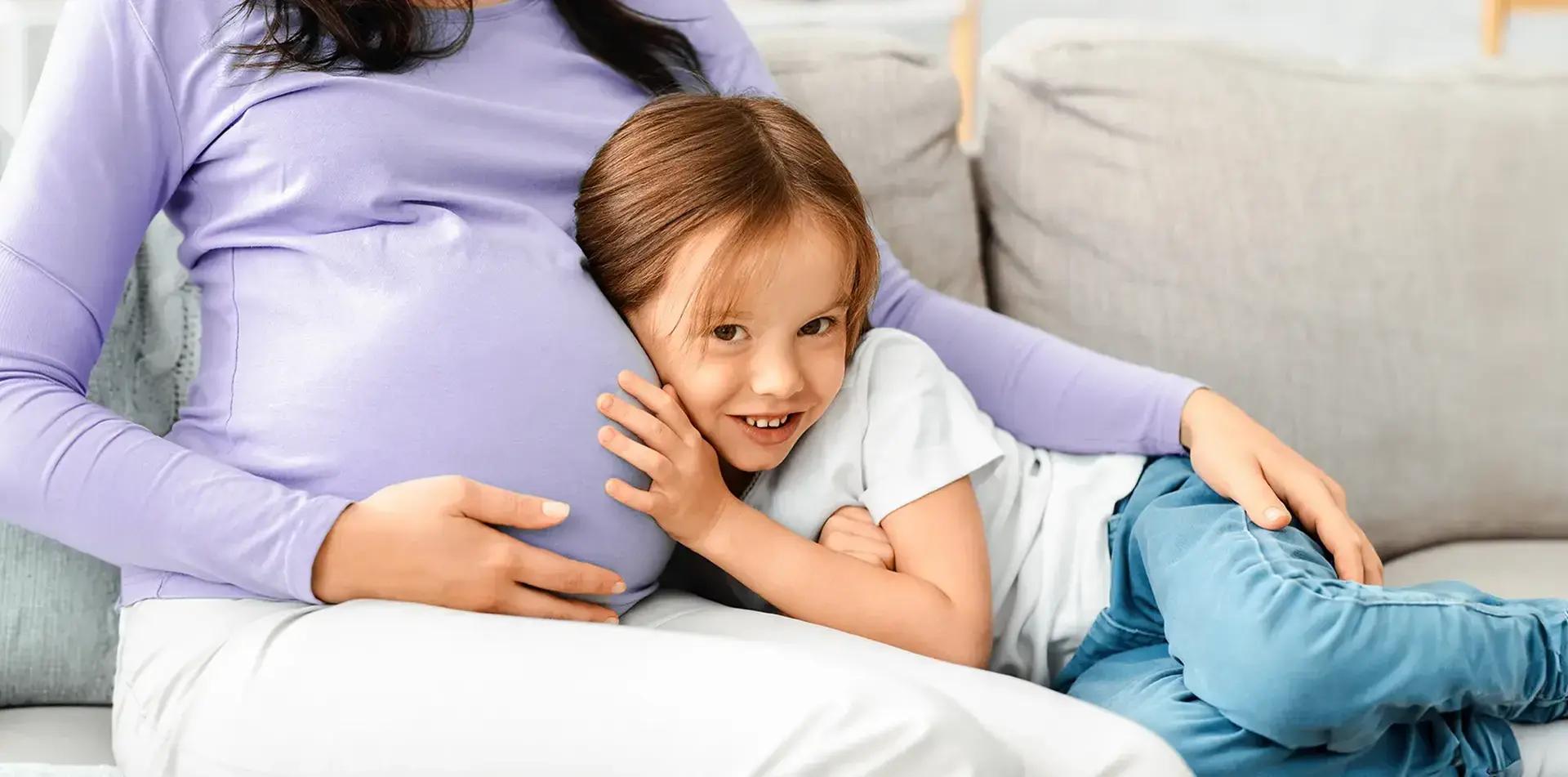 момиченце гушнато до бременна жена