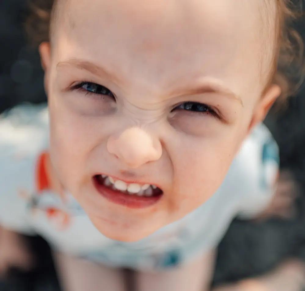 Малко дете с намръщено лице, гледащо нагоре.