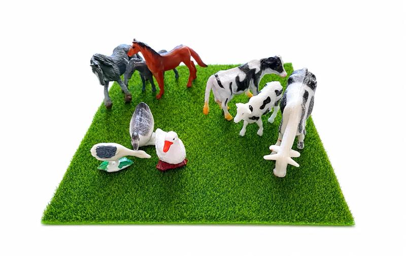 Миниатюрни играчки на животни върху зелена изкуствена трева