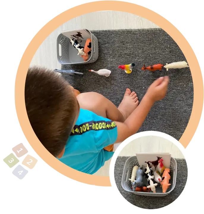 Малко дете играе с фигурки на животни върху сив килим