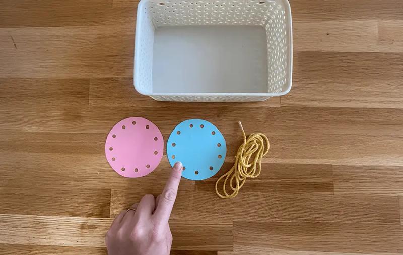 бял панер поставен до розов и син кръг с дупки и връвчица