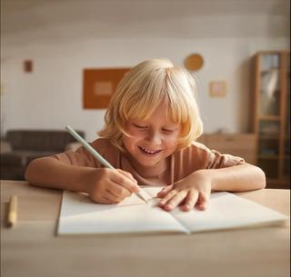 дете пише с молив върху тетрадка