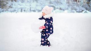 Дете играе с голяма снежна топка