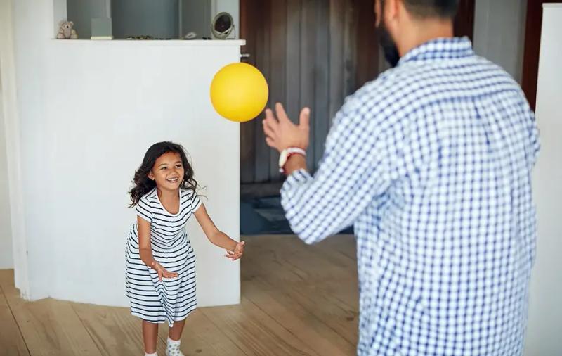 момиченце и възрастен играят с топка