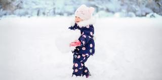 Дете играе с голяма снежна топка
