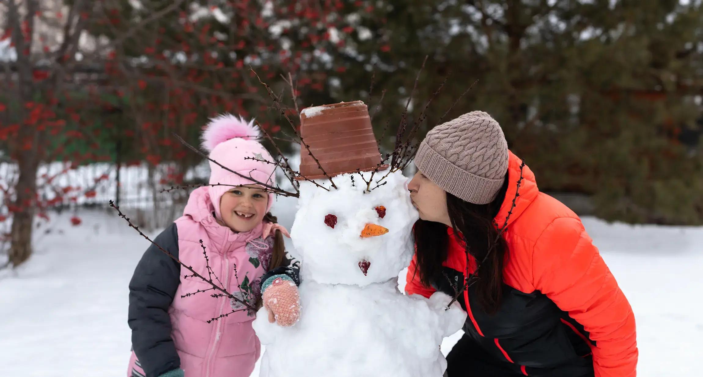 майка и дете се снимат със снежен човек
